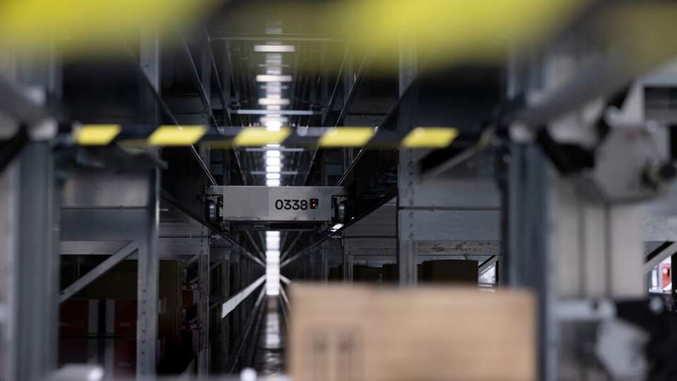 Intralogistik neu gedacht  seitlicher Blick auf den Transportshuttle mit dem Baumer Sensor OT300, der im Vorbeifahren Lagerabteile auf Belegung und Positionierung der Produkte abtastet.