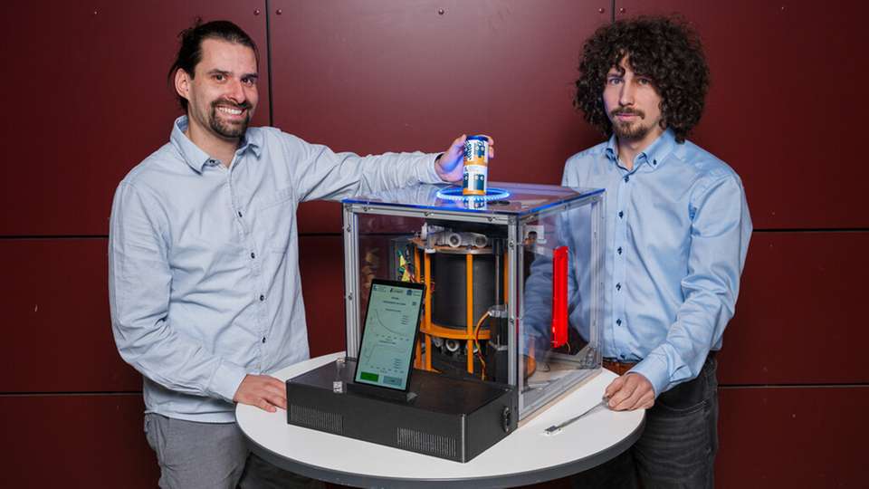 Wie die Elastokalorik kühlt, zeigt das Forschungsteam auf der diesjährigen Hannover Messe mit dem ersten Kühlschrank-Prototyp. Die Doktoranden Lukas Ehl (links) und Ivan Trofimenko (rechts) forschen mit an der neuen Klimatechnologie.