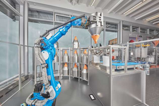 Roboterbasierte Rohstoff-Automation: der Rolog von Azo mit den DLEs und dem orangen Dosierorgan eDos.