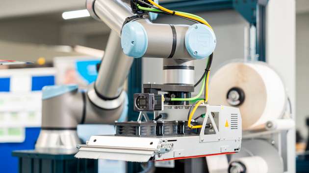 Robotergestütztes Etikettiersystem mit Kameraprüfung appliziert Etiketten automatisiert auf Verpackungen – flexible Lösung für industrielle Produktionslinien.