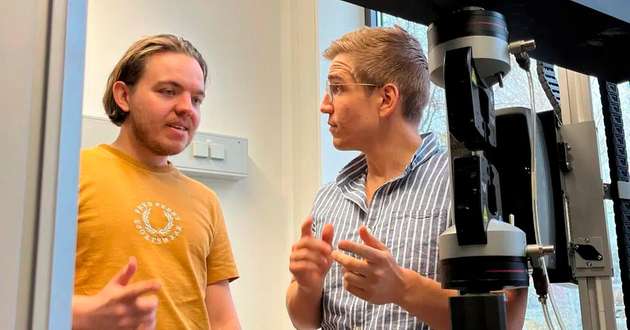 Christoph Fornacon-Wood und Prof. Dr. Alex J. Plajer an einer Zugprüfmaschine, mit der man mechanische Eigenschaften von Polymeren untersuchen kann.