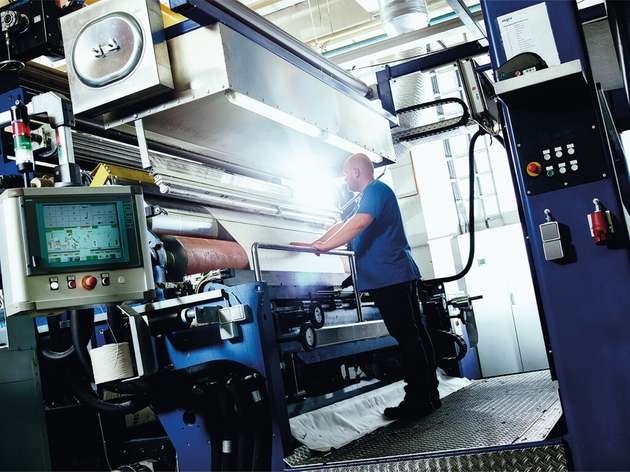 Ein Mitarbeiter von Setex bedient eine moderne Textilveredelungsanlage mit digitaler Steuerung.