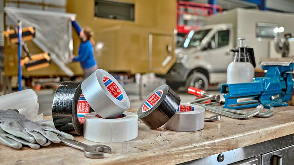 Tesa-Klebebänder in verschiedenen Ausführungen auf einer Werkbank – typische Einsatzmittel für Abdecken, Befestigen und Reparieren in industriellen und handwerklichen Anwendungen.