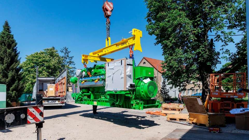 Der Gasmotor, der die KWK-Einheit der iKWK-Anlage Gera-Langenberg bildet, wird mit einem Kran vom Lkw heruntergehoben und für die Einbringung in das Heizhaus vorbereitet.
