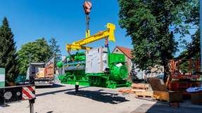 Der Gasmotor, der die KWK-Einheit der iKWK-Anlage Gera-Langenberg bildet, wird mit einem Kran vom Lkw heruntergehoben und für die Einbringung in das Heizhaus vorbereitet.