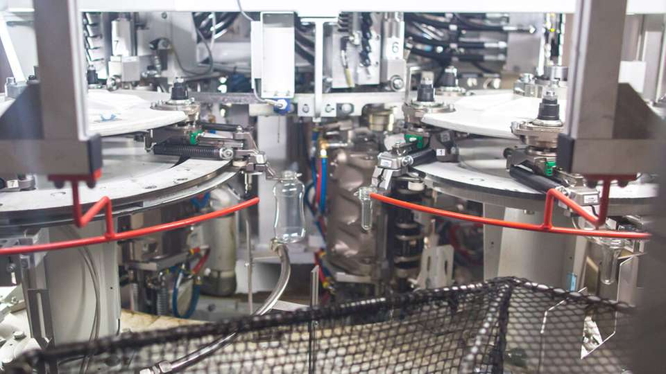 Die Blasmaschine produziert PET-Behälter im laufenden Prozess: Mit Preferential Heating lassen sich flache Top-Down-Flaschen für Saucen bei hoher Leistung fertigen und gleichzeitig Materialeinsatz sowie Energiebedarf reduzieren.