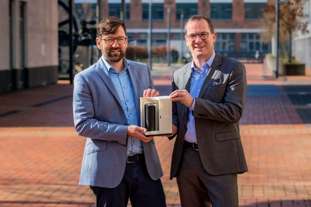 Auf dem Foto sind Dr. Hendrik Schaede-Bodenschatz (Geschäftsführer von Adaptive Balancing Power) und Dr. Andreas Hoffknecht (Technik-Geschäftsführer der DB Energie) mit dem Modell eines Schwungmassenspeichers zu sehen.
