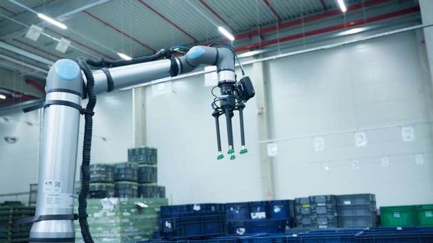 Der Cobot greift die Behälter mit einem Sauggreifer und stapelt sie auf Paletten.