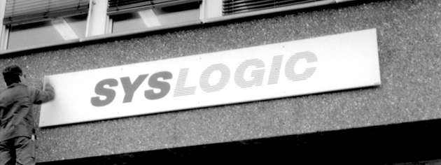 Der Anfang einer Erfolgsgeschichte: Ein historisches Foto zeigt die Montage des Syslogic-Firmenschilds – 40 Jahre später ist das Unternehmen internationale Spezialistin für robuste Embedded-Systeme.
