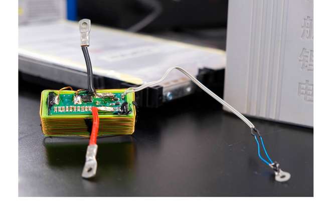 Die grüne Platine enthält den elektronischen Schaltkreis, mit dem die Forschenden Sensordaten über die vorhandenen Stromanschlüsse einer Batteriezelle übertragen. Die Batteriezelle befindet sich im Hintergrund.