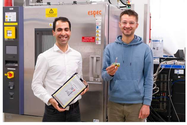 Dr. Hamzeh Beiranvand (links) hält die Batteriezelle, Johannes Diers (rechts) den eigens entwickelten elektronischen Schaltkreis. Gemeinsam bilden sie das Modell einer „sprechenden Batterie“.