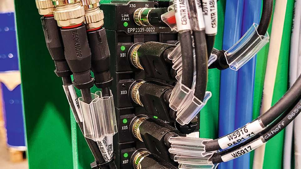EtherCAT P-Box-Module verbinden die dezentralen I/Os für Achsen, Greifer und Sensoren über nur ein Kabel für Kommunikation und Power (rot/schwarz) mit der Steuerung im Schaltschrank.