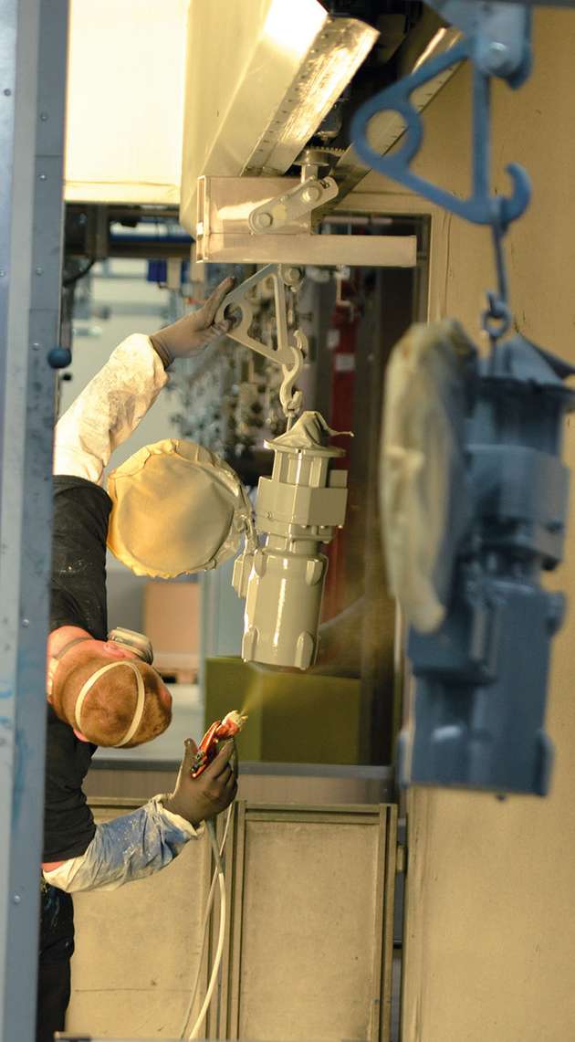 Von der Montage eilen die Getriebe zur Lackieranlage. In vier Straßen verteilen sie sich, nach Farben und Dringlichkeit sortiert. Je nach Kundenbedarf werden bis zu fünf Schichten aufgetragen – alles per Hand. Denn ein Roboter könnte die teilweise sehr komplexen Konturen mit ihren Zwischenräumen nicht so gleichmäßig lackieren.