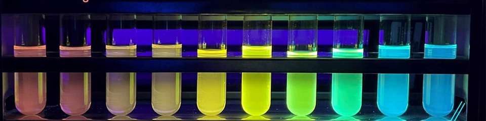 Reagenzgläser, die die neuen Silikon-Copolymere enthalten, getrennt nach Kettenlänge, von lang bis kurz, liefern den visuellen Beweis für die unterschiedliche Bandlücke im neuen Halbleitersilikon. Bei Bestrahlung mit UV-Licht entsteht ein Regenbogen von Bechern, da sich die längeren Kettenlängen zum roten Ende des elektromagnetischen Spektrums hin verschieben und weniger Energie benötigen, um Licht mit niedrigeren Energien zu absorbieren und auszusenden.